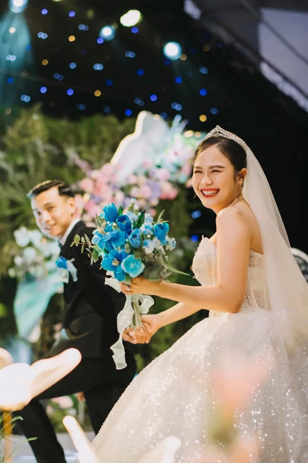 Cô dâu cười rạng rỡ cầm bó hoa xanh